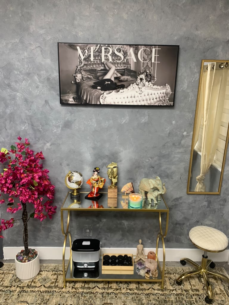Elegant studio details with a framed Versace print, gold console table and pink blossom tree
