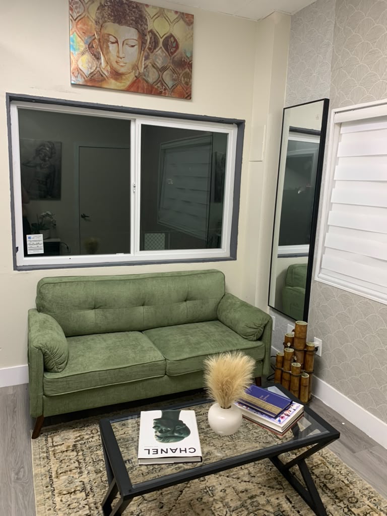 Calm guest lounge with a green velvet sofa, Buddha artwork and a glass coffee table